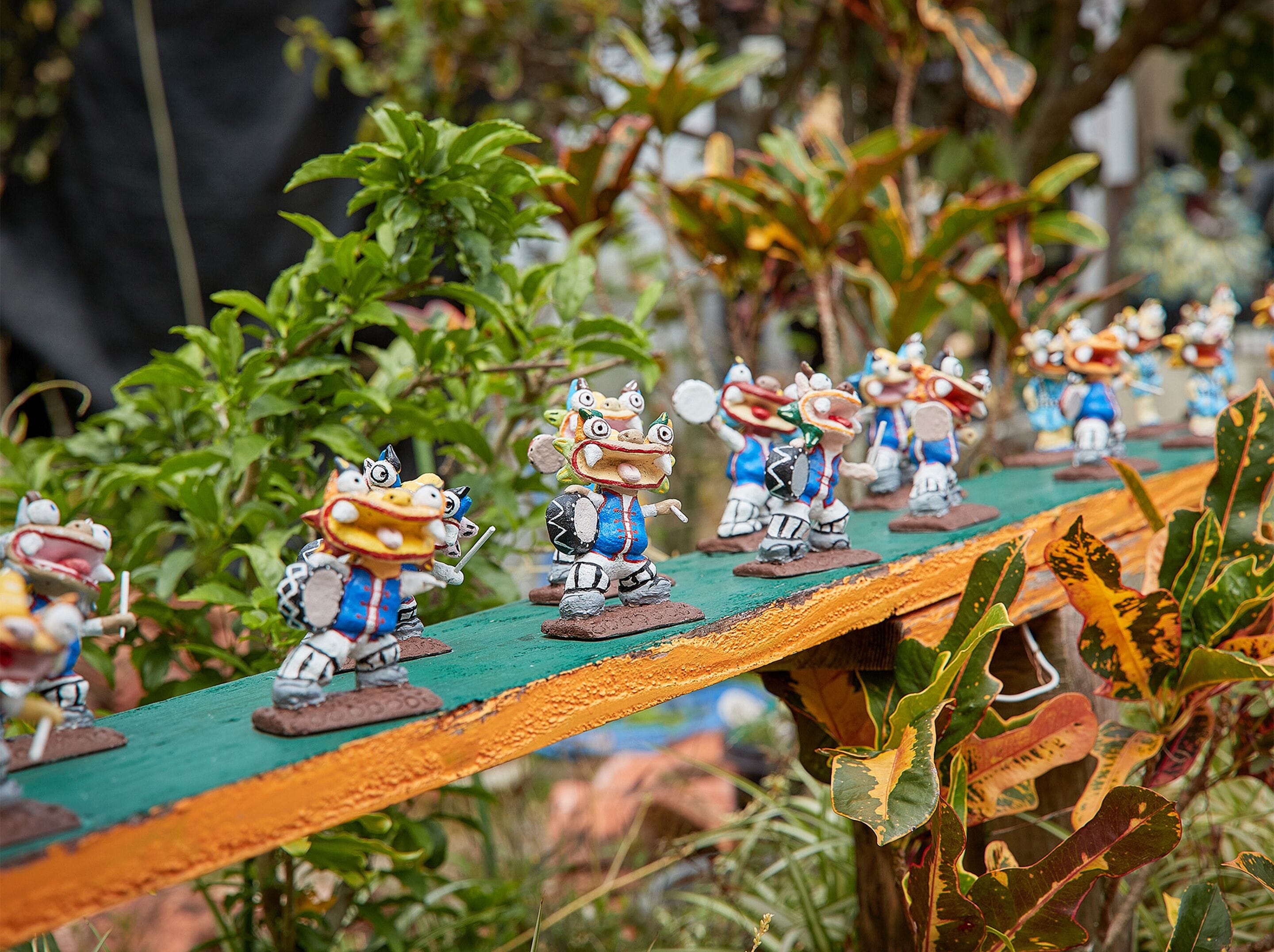 Una hilera de figuritas en miniatura sobre una plataforma de madera.