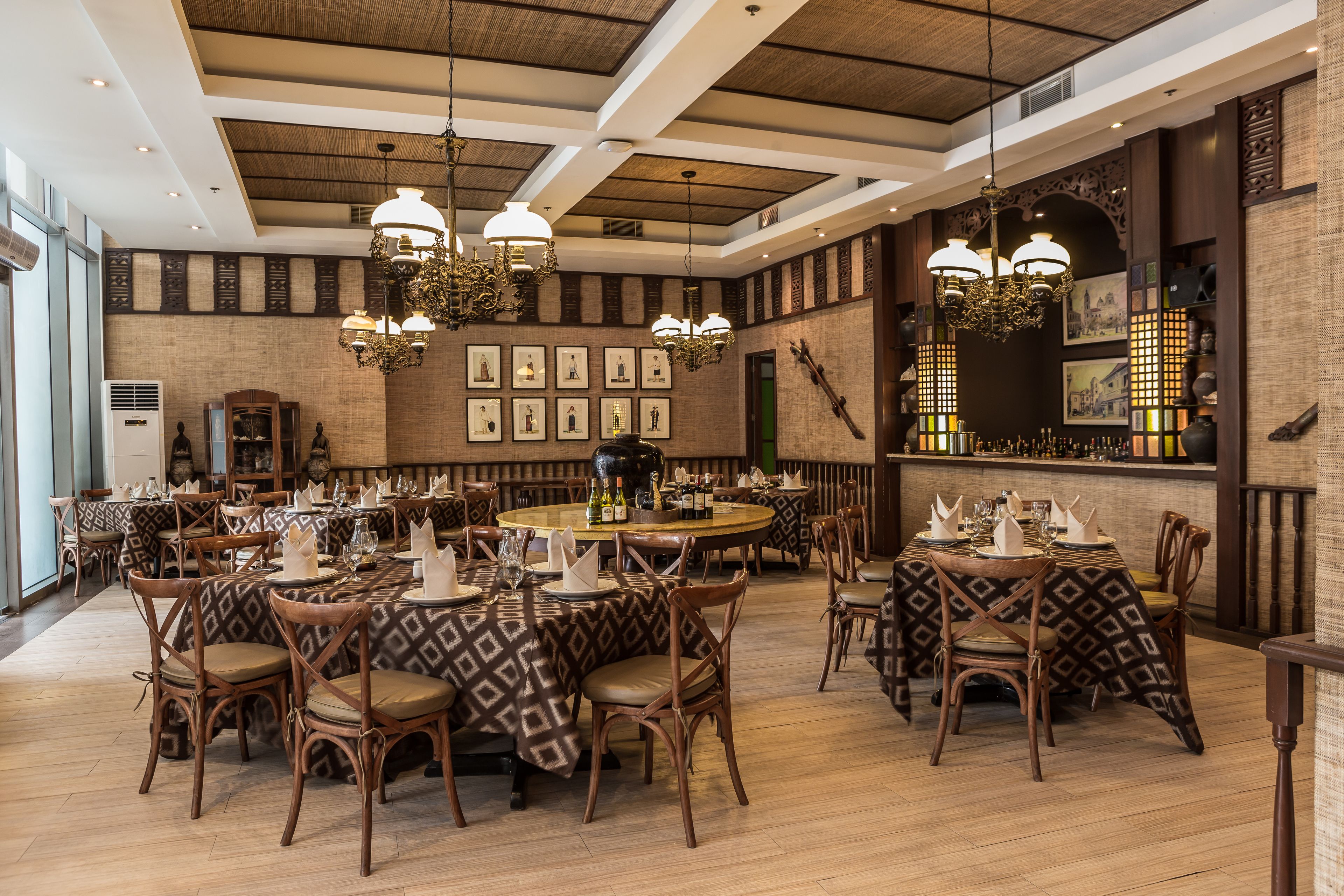 Un ristorante con tavoli rotondi, sedie in legno e tovaglie decorate.