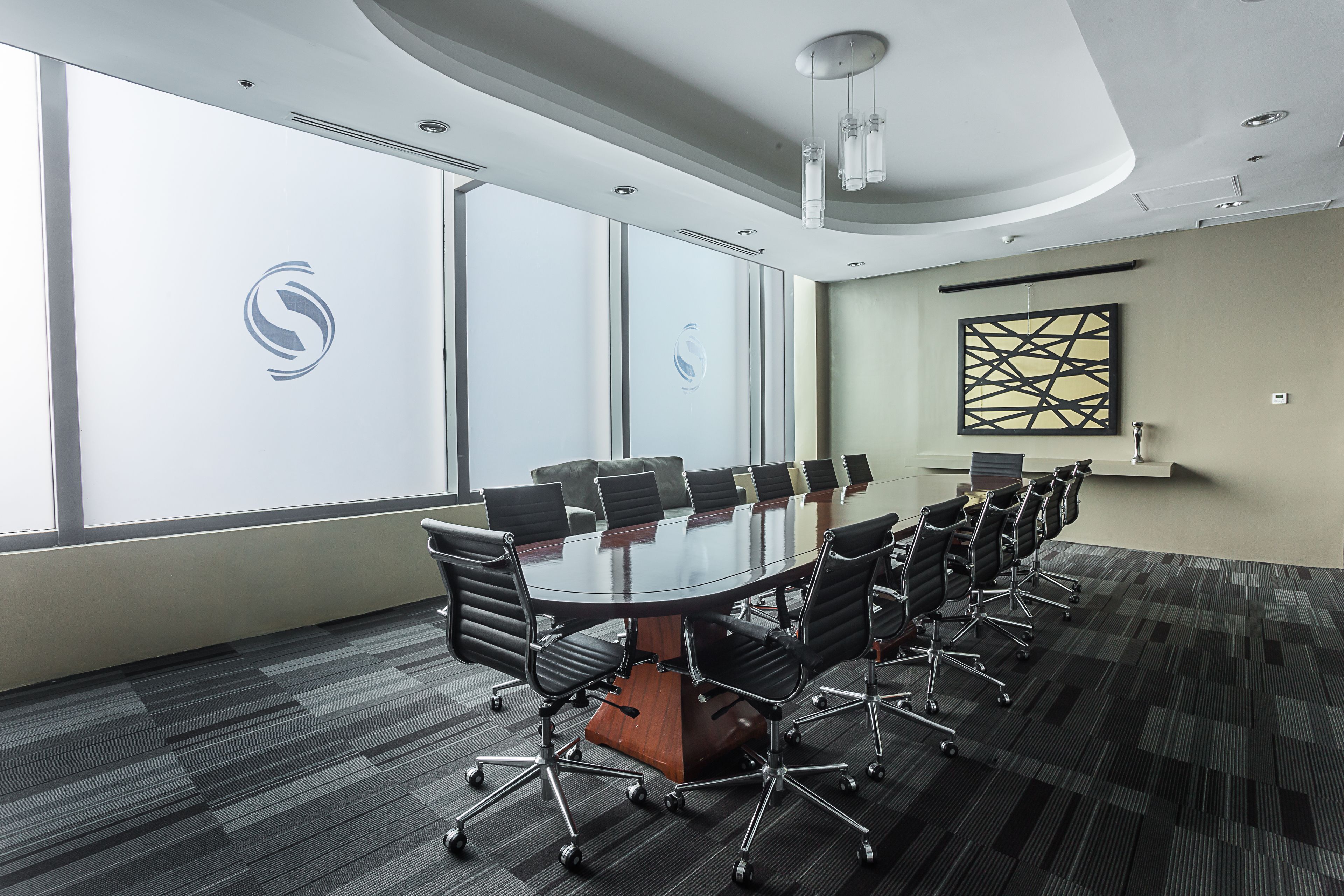 Une salle de conférence dotée d’une grande table ovale, de chaises noires et d’un design moderne.