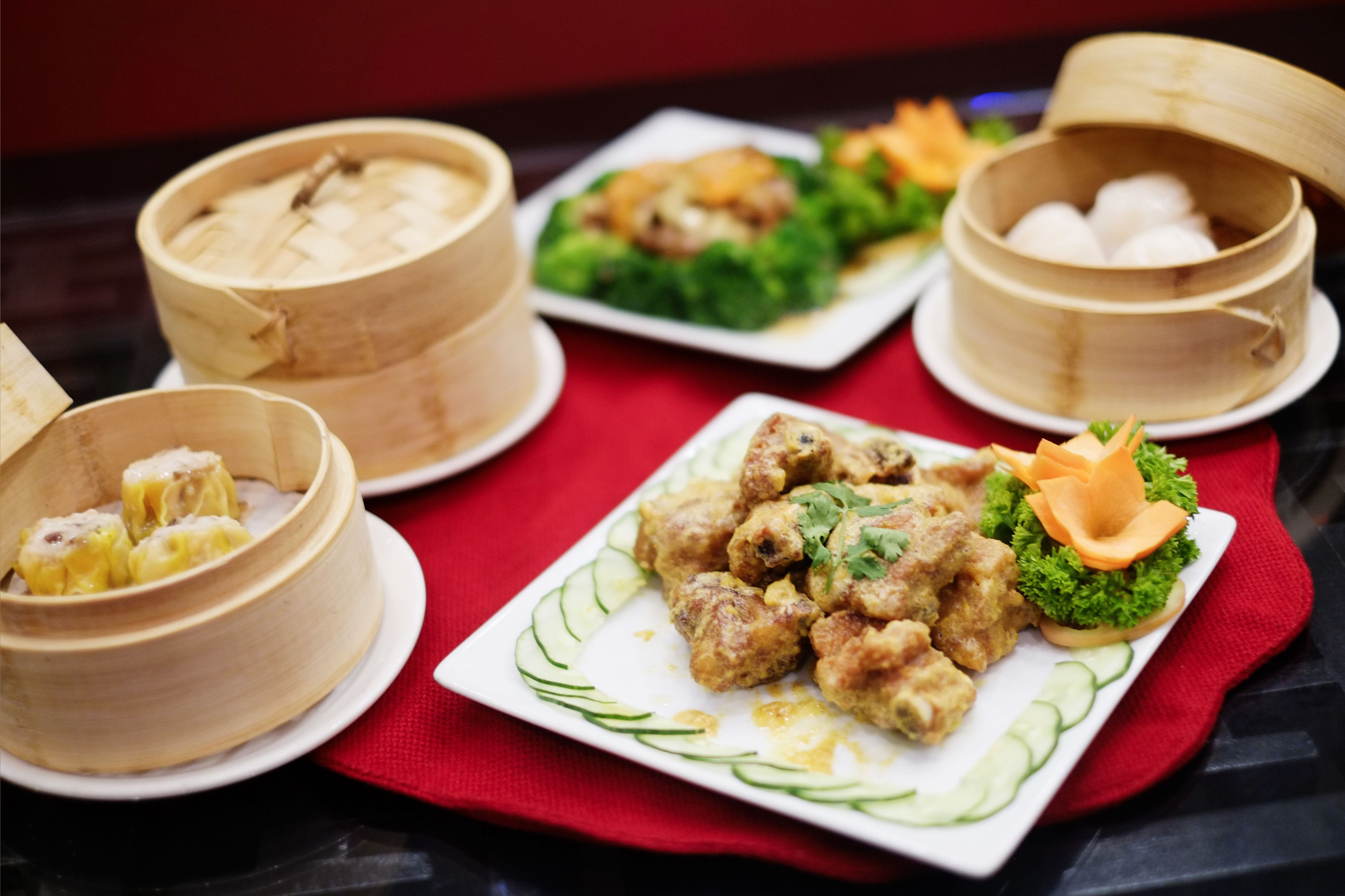 Una mesa con varios platos, incluyendo dumplings, una fuente de albóndigas y un plato con verduras.