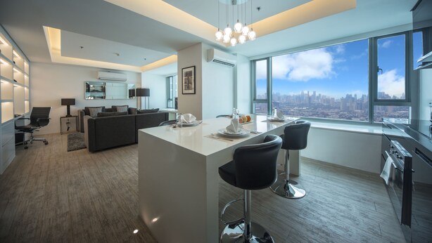Una cocina moderna con una isla grande, taburetes de bar y vistas a la ciudad.