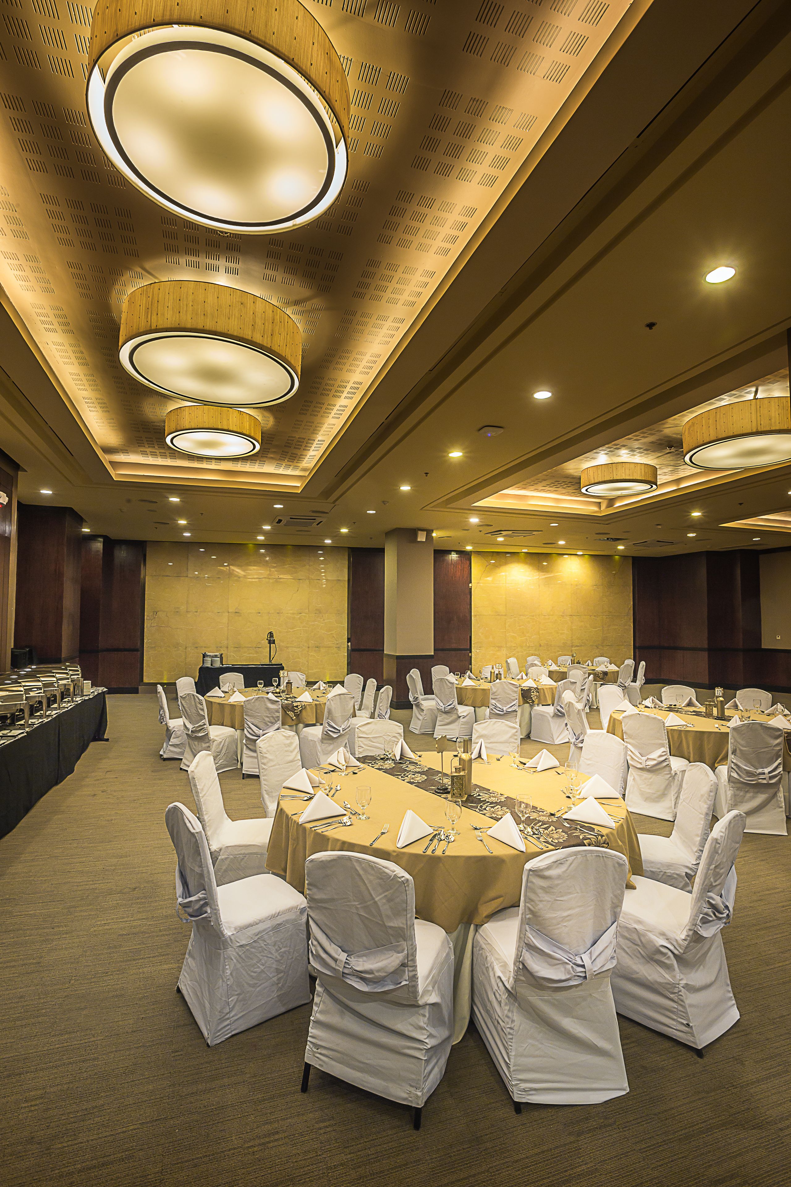 A conference room with round tables, white chairs, and a stage.