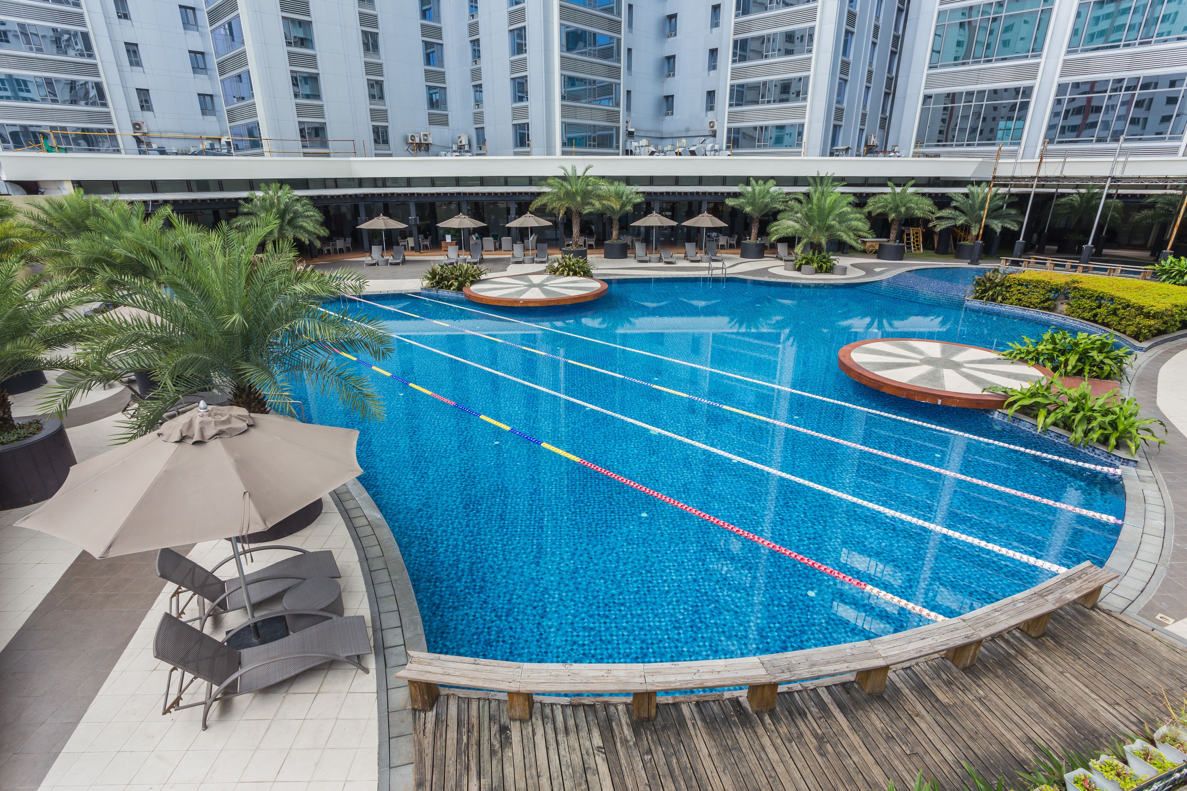Un hôtel moderne doté d’une grande piscine intérieure, de chaises longues et de palmiers.