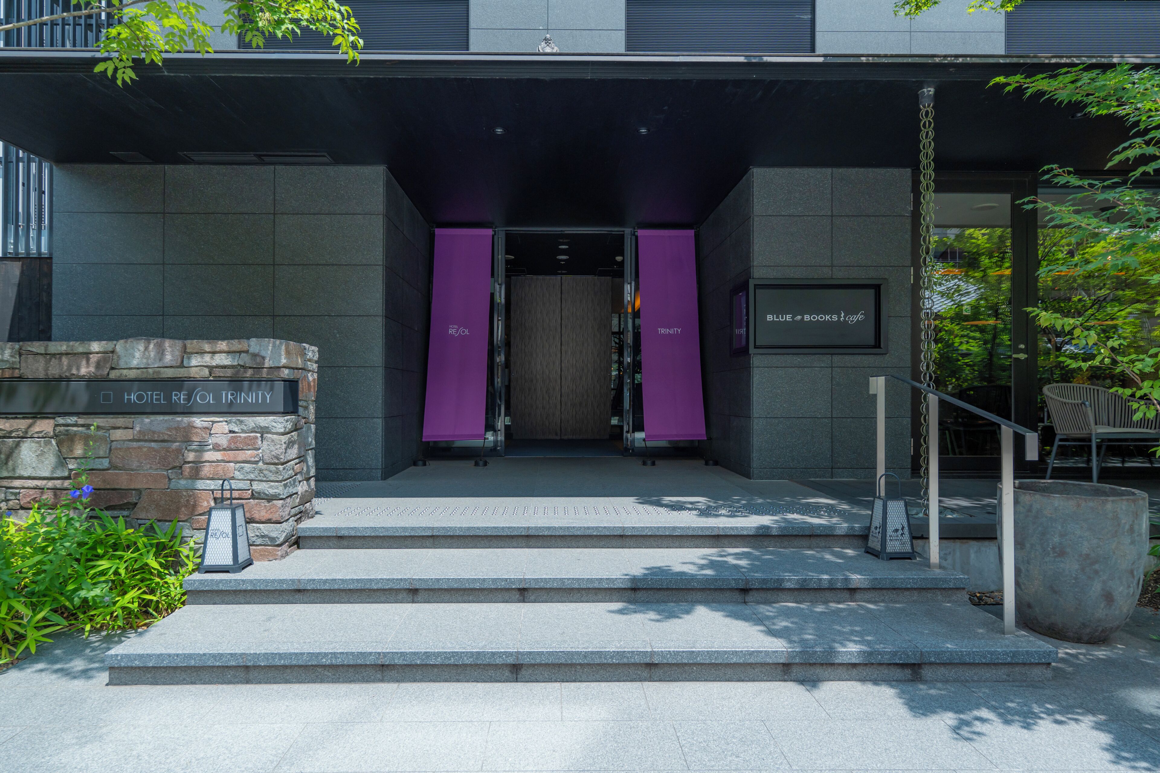 A hotel entrance with a stone facade, a wooden door, and a sign for 'BLUE BOOKS Cafe'.