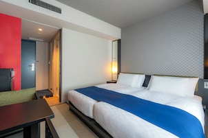 Una habitación de hotel con cama, mesita de noche y un escritorio con silla.
