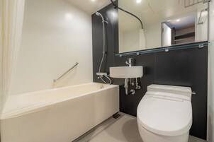 A modern bathroom with a bathtub, a toilet, and a glass shelf above the sink.