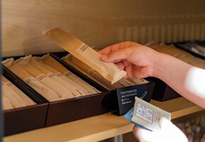 A hand selecting a toothbrush from a box labeled 'TOOTHBRUSH with TOOTHPASTE'.