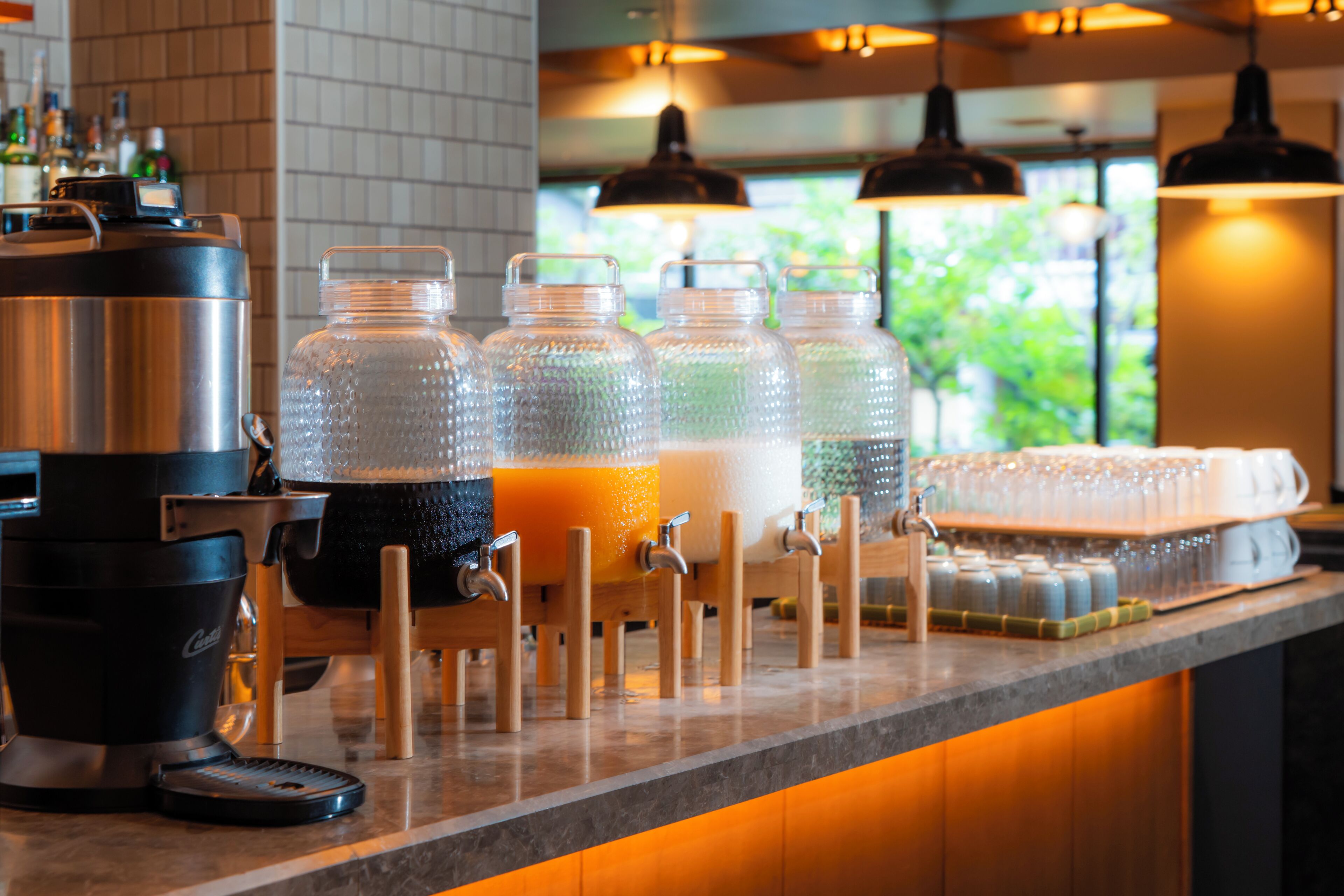 A bar area with a coffee machine, multiple beverage dispensers, and a counter with glasses.