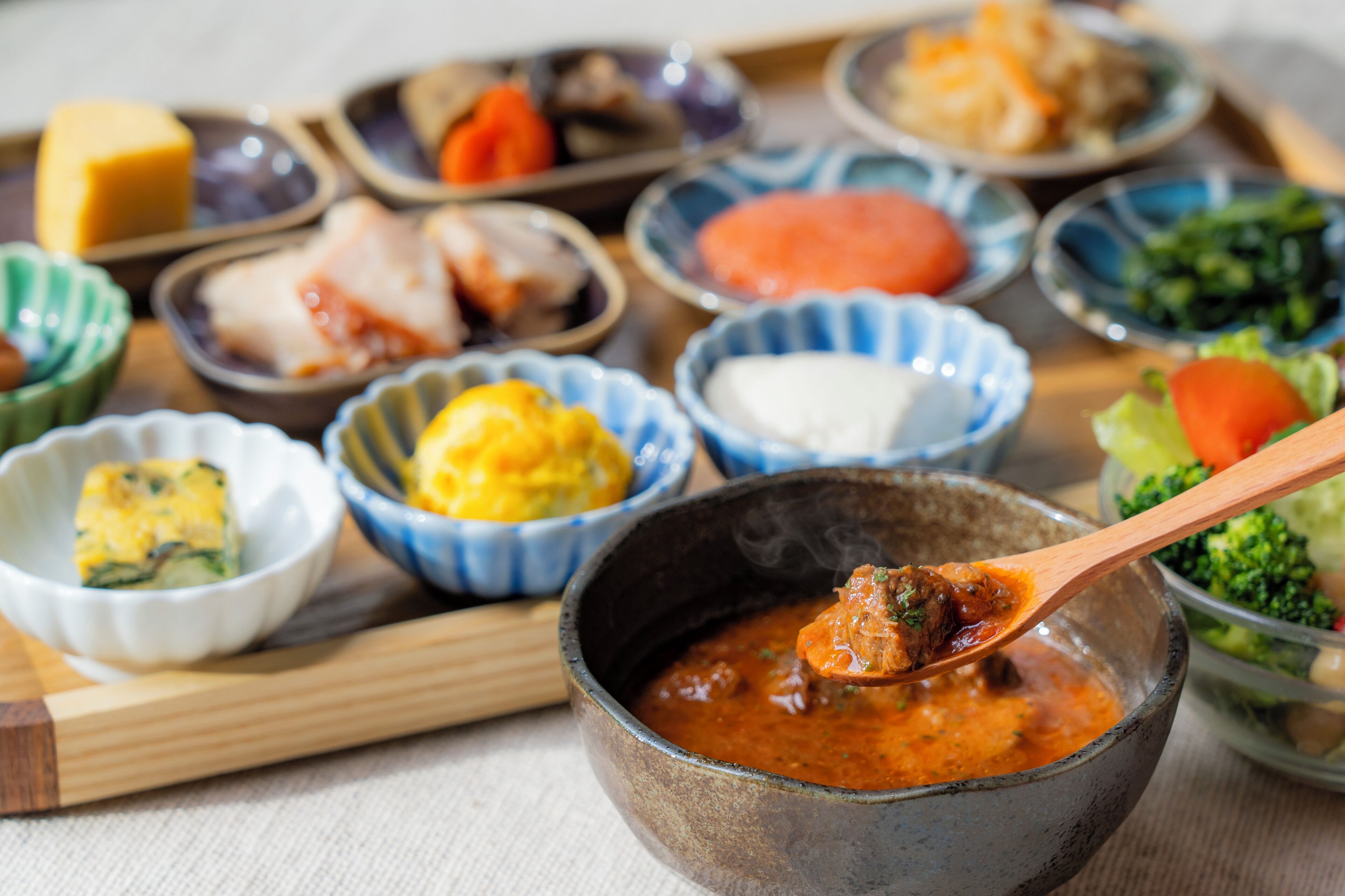 A variety of dishes in small bowls, including a bowl of soup with a spoon.
