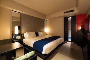 Ein Hotelzimmer mit Bett, Nachttisch, Spiegel und Blick ins Freie.
