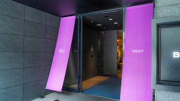 A hotel entrance with a glass door and pink signage.