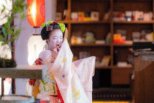 Une pièce de style japonais traditionnel, avec une bibliothèque en bois, une lanterne rouge et une personne vêtue d’un costume traditionnel.