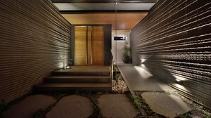 A modern interior with a wooden door, steps leading to a platform, and a wall with a textured pattern. - Shanyifang Resort (Yuanshan)