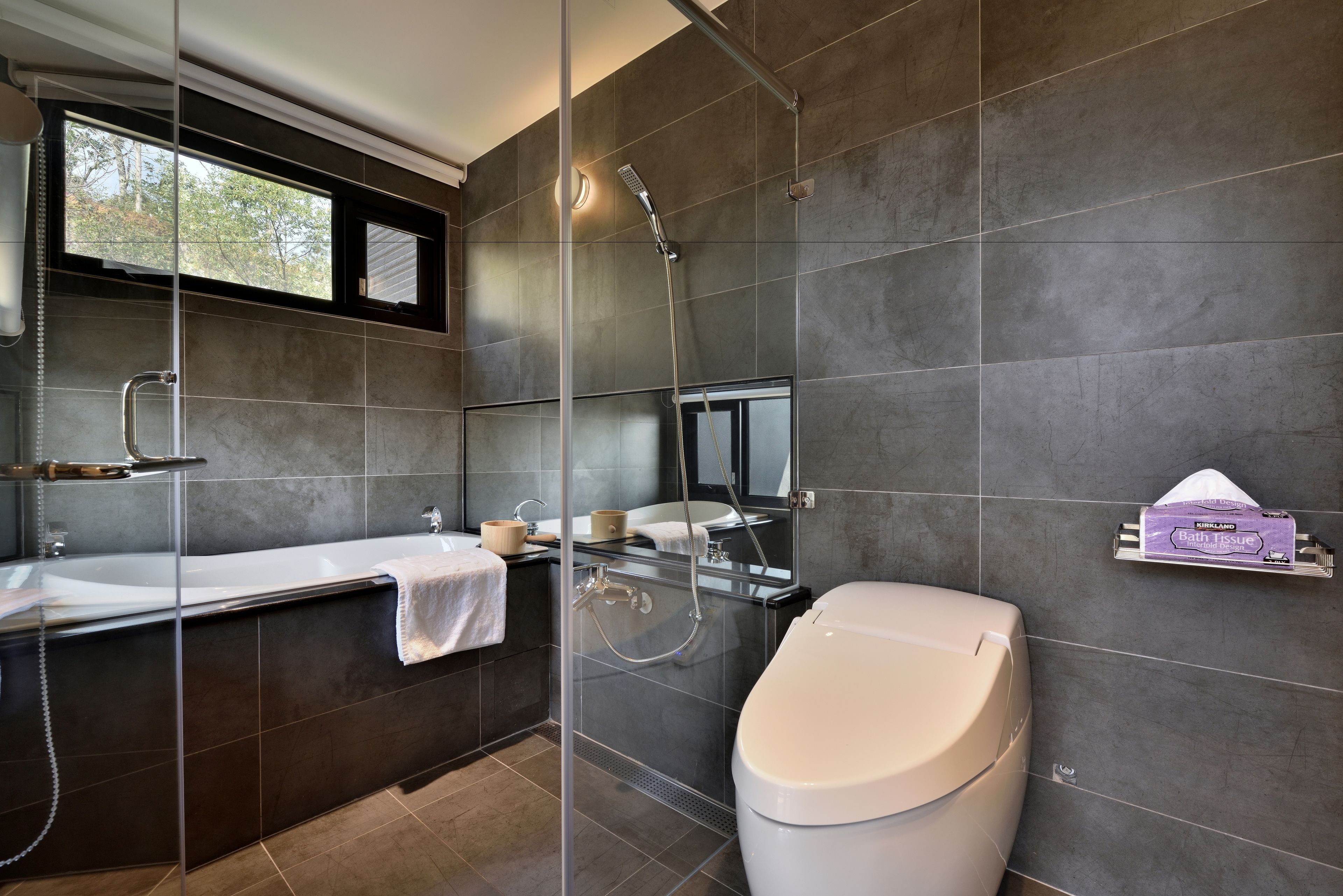 Un baño moderno con ducha de vidrio, bañera y retrete.