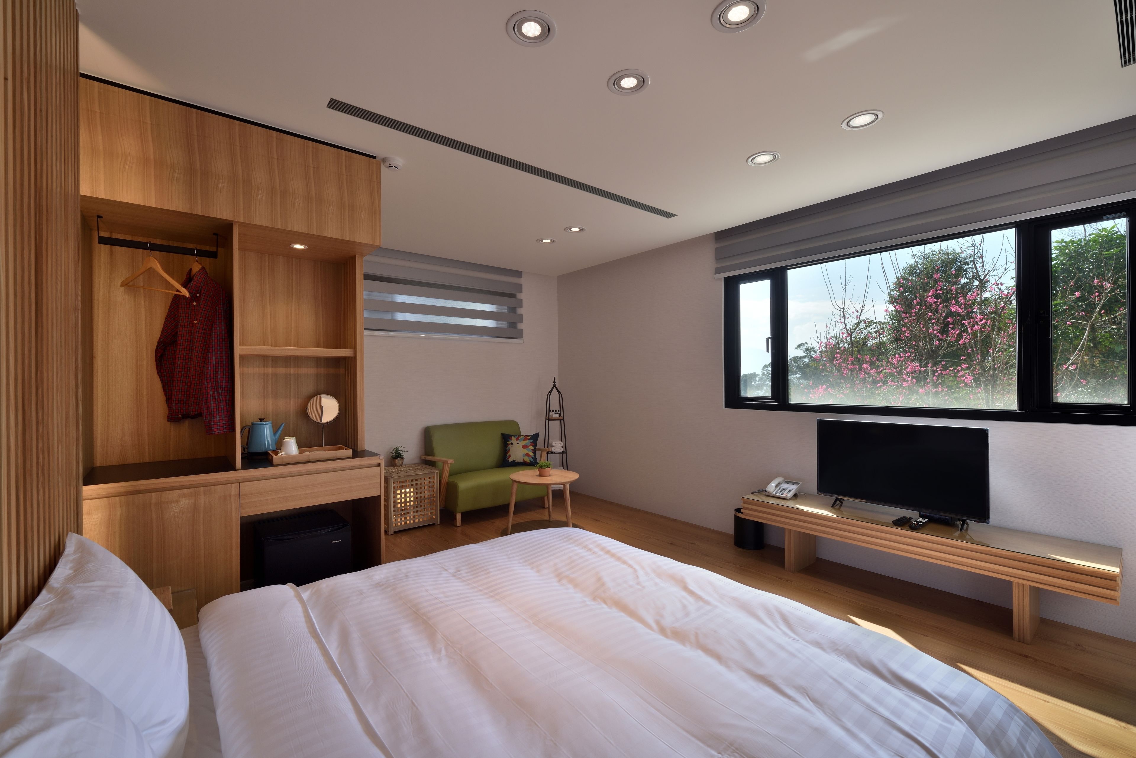 Ein modernes Hotelzimmer mit einem großen Bett, einem Fernseher, einem Holztisch und einem grünen Sofa.