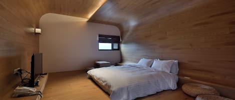 Un dormitorio moderno con paredes de madera, una cama, una mesita de noche y un televisor.