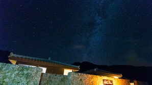A stone building with a sign illuminated by warm lighting, under a starry night sky. - Stardust Villa Milky Way (Ishigaki)