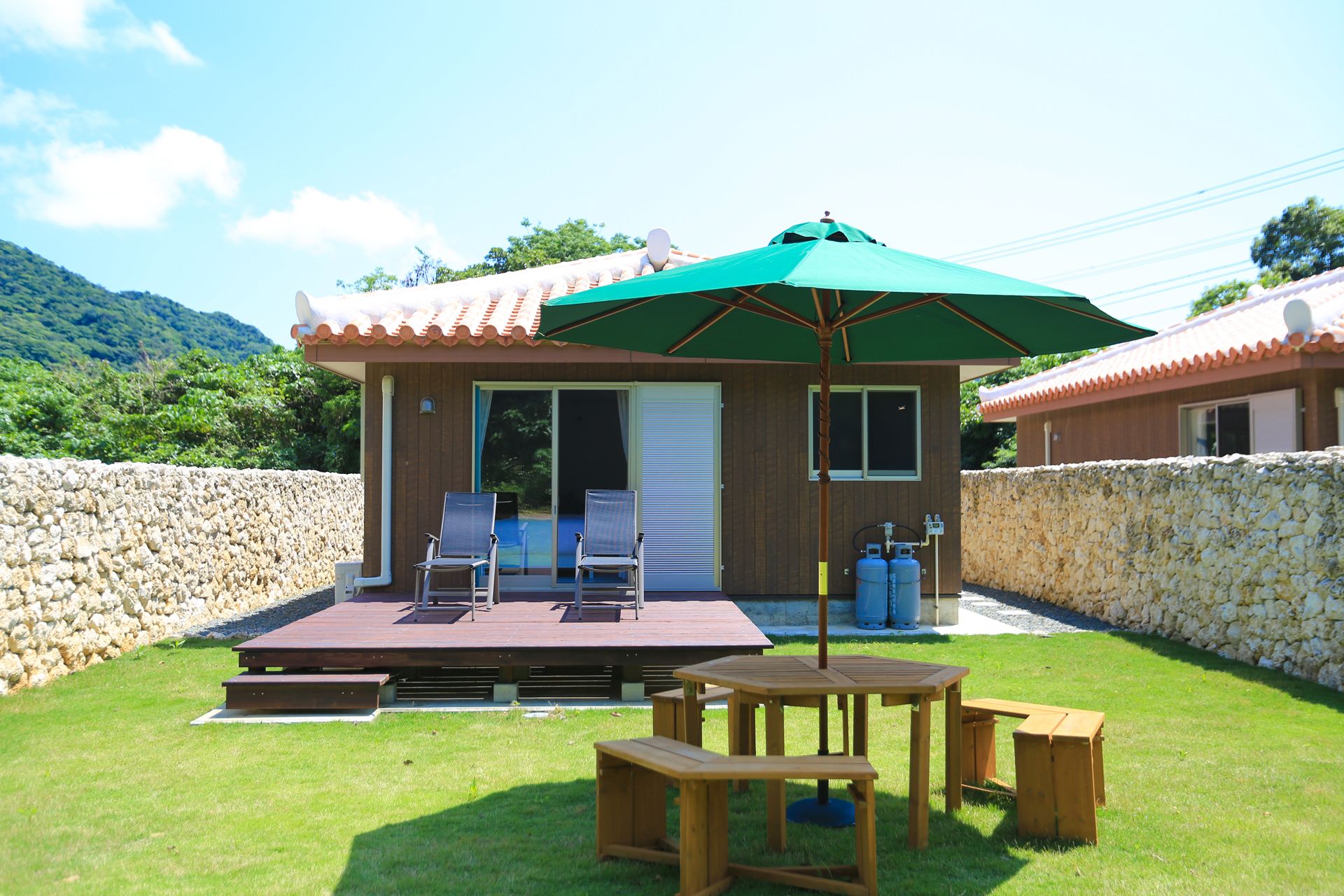 A wooden building with a patio area, including a table and chairs, and a green umbrella.