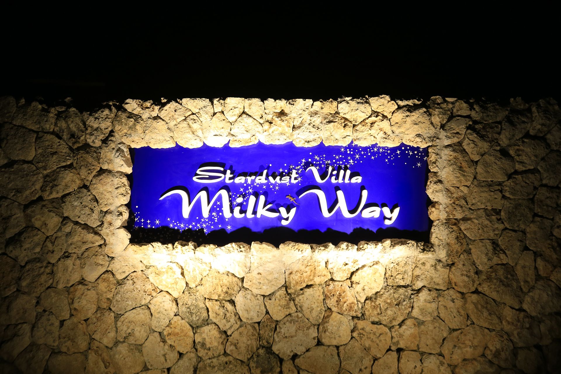 A sign with the text "Standstill Villa Milky Way" against a stone wall background.