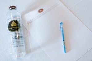 A clear plastic bottle with a label, a blue pen, and a white sheet of paper with printed text. - The Singora Hotel (Songkhla)