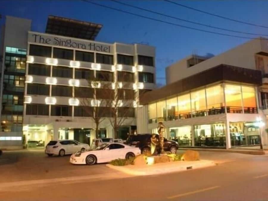 The Singora Hotel with a modern facade, multiple floors, and a well-lit entrance.