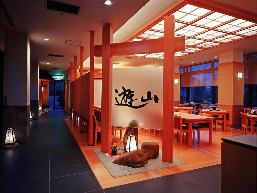 A traditional Japanese restaurant interior with wooden beams, tatami mats, and a central wall with calligraphy.