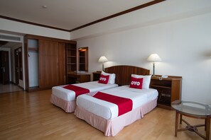 A hotel room with two beds, wooden wardrobe, bedside tables, and a glass table. - Ayutthaya River View Hotel (Ayutthaya)