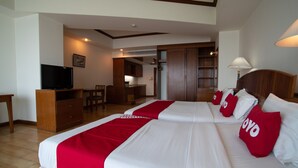 Una habitación de hotel con dos camas, televisión, escritorio y zona de comedor.