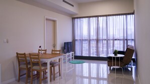 A modern living room with a dining area, a ceiling fan, a TV, and a large window with sheer curtains. - Iconic Homestay (Kota Kinabalu)
