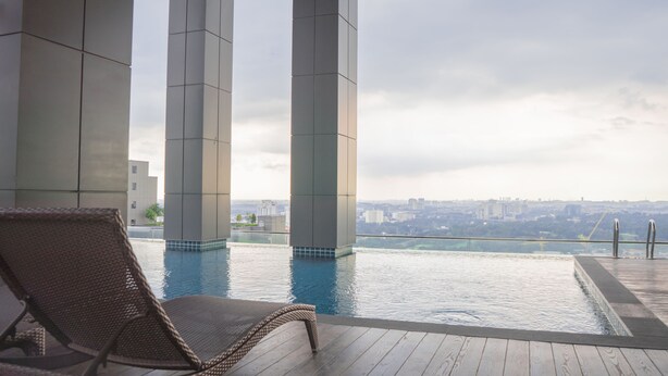 A pool area with a lounge chair, large pillars, and a city view. - Iconic Homestay (Kota Kinabalu)