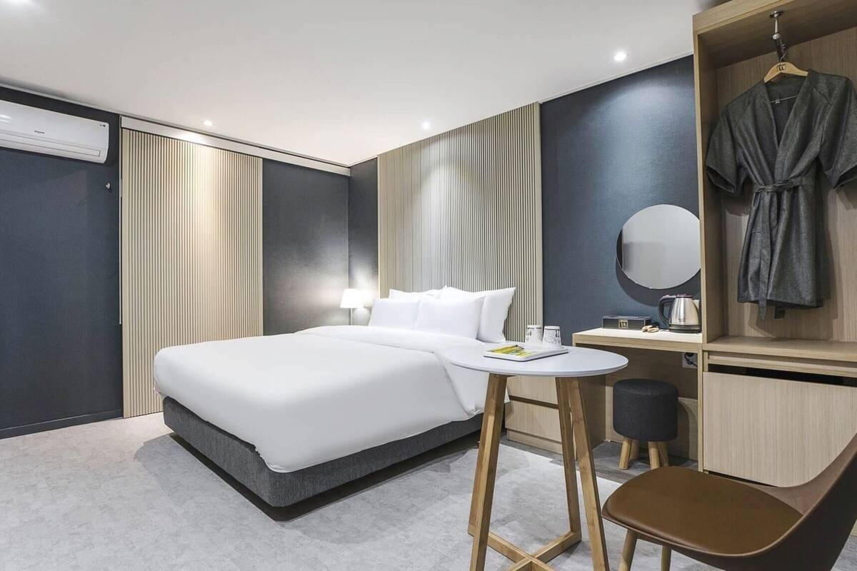 Une chambre d’hôtel avec un lit, une table de chevet, une chaise et un peignoir suspendu à un porte-manteau.