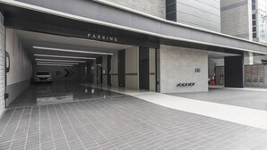 A modern parking garage entrance with a clear "PARKING" sign, a car parked inside, and a fire extinguisher mounted on the wall. - JJ Hotel (Seongnam)
