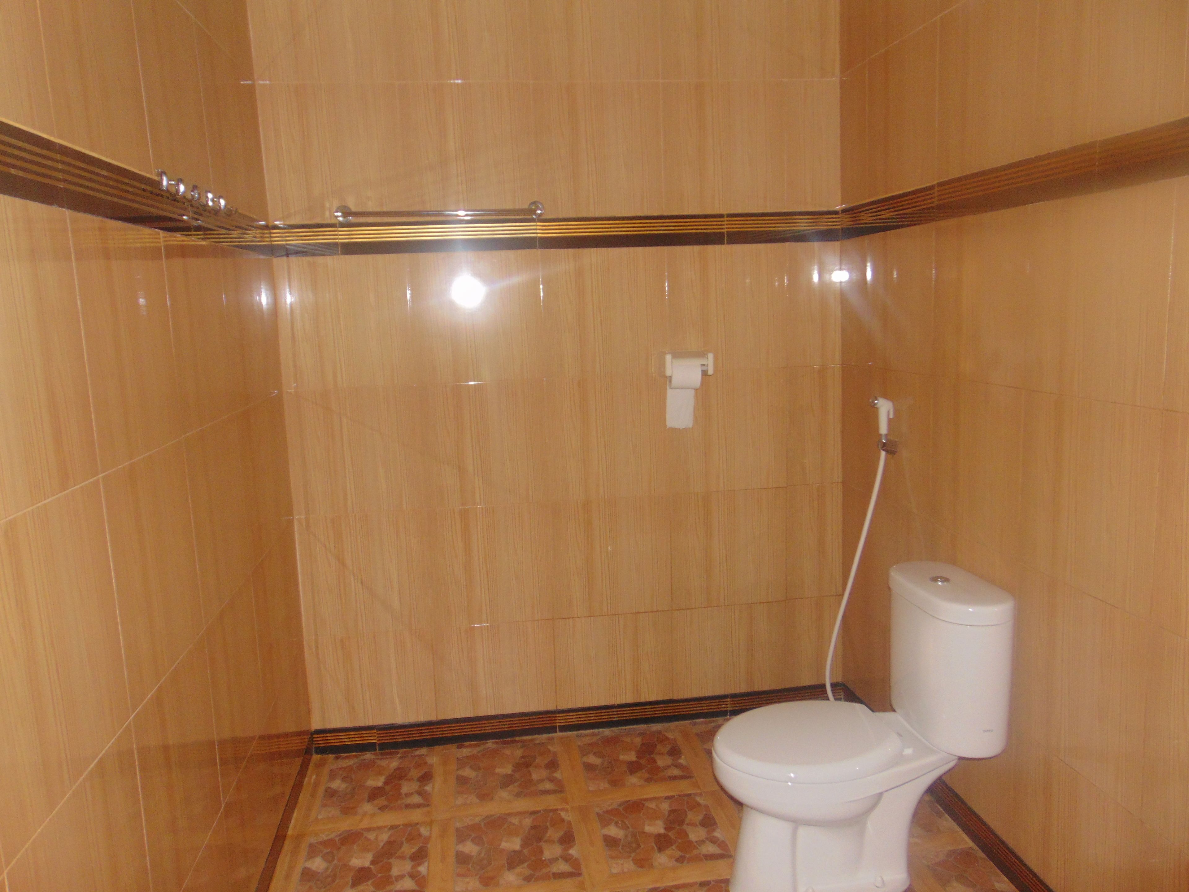 A bathroom with a toilet, a shower, and a tiled floor.