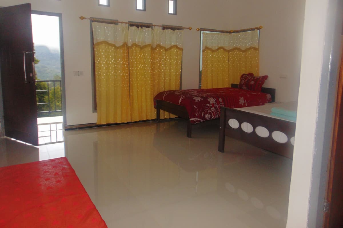 A bedroom with a bed, a red rug, and a window with curtains.