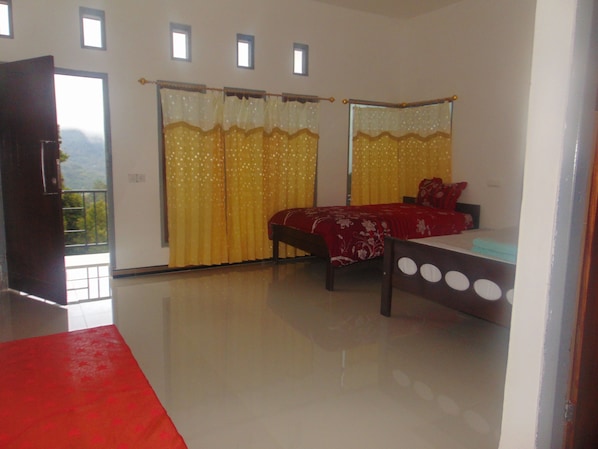 A bedroom with a bed, a red rug, and a window with curtains.