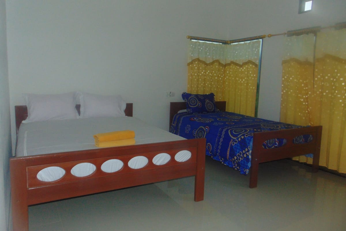 A bedroom with two beds, one with a white bedspread and the other with a blue bedspread.