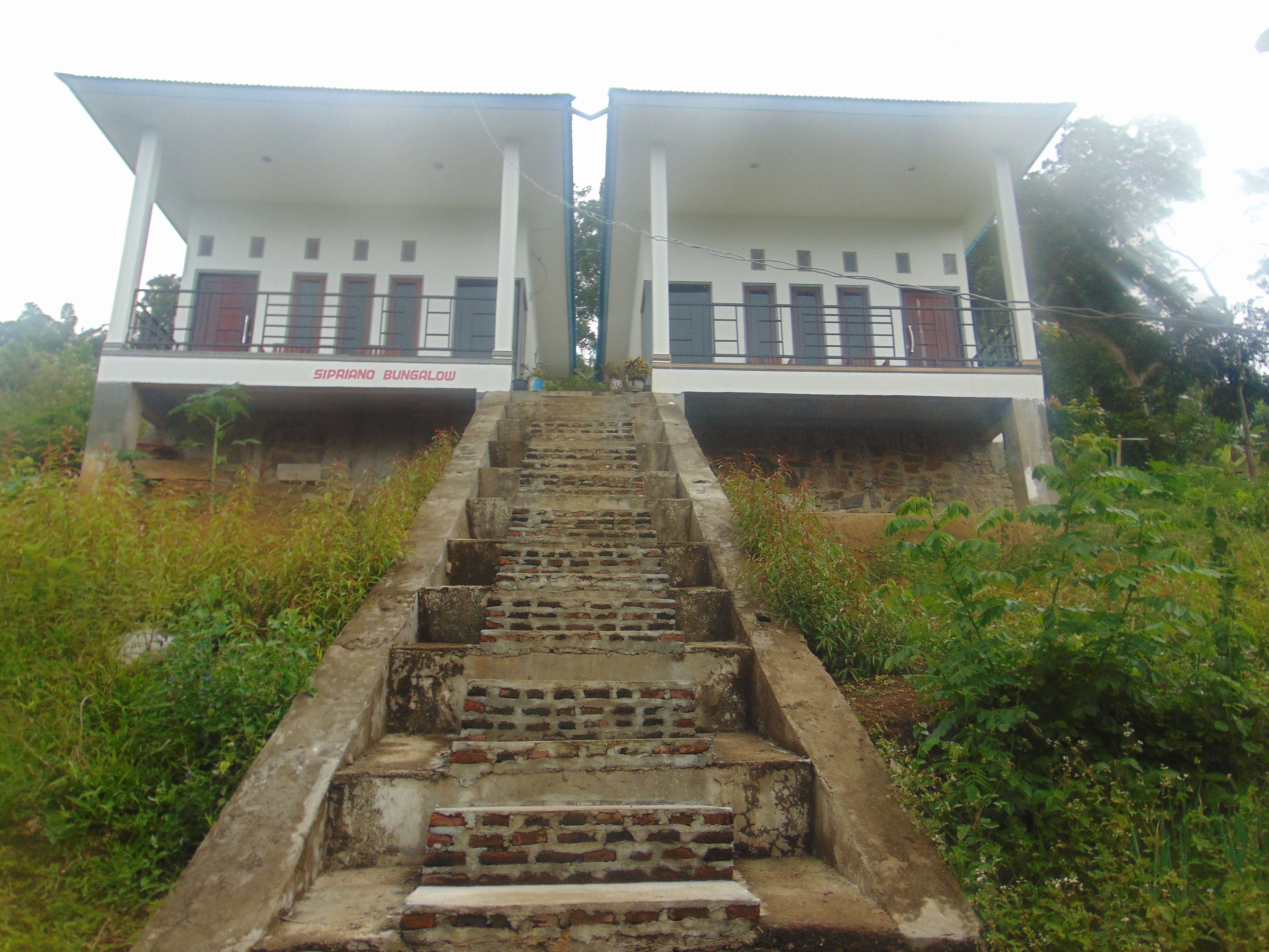 A set of outdoor stairs leading to a bungalow with a sign reading "GIPRIANO BUNGALOW".