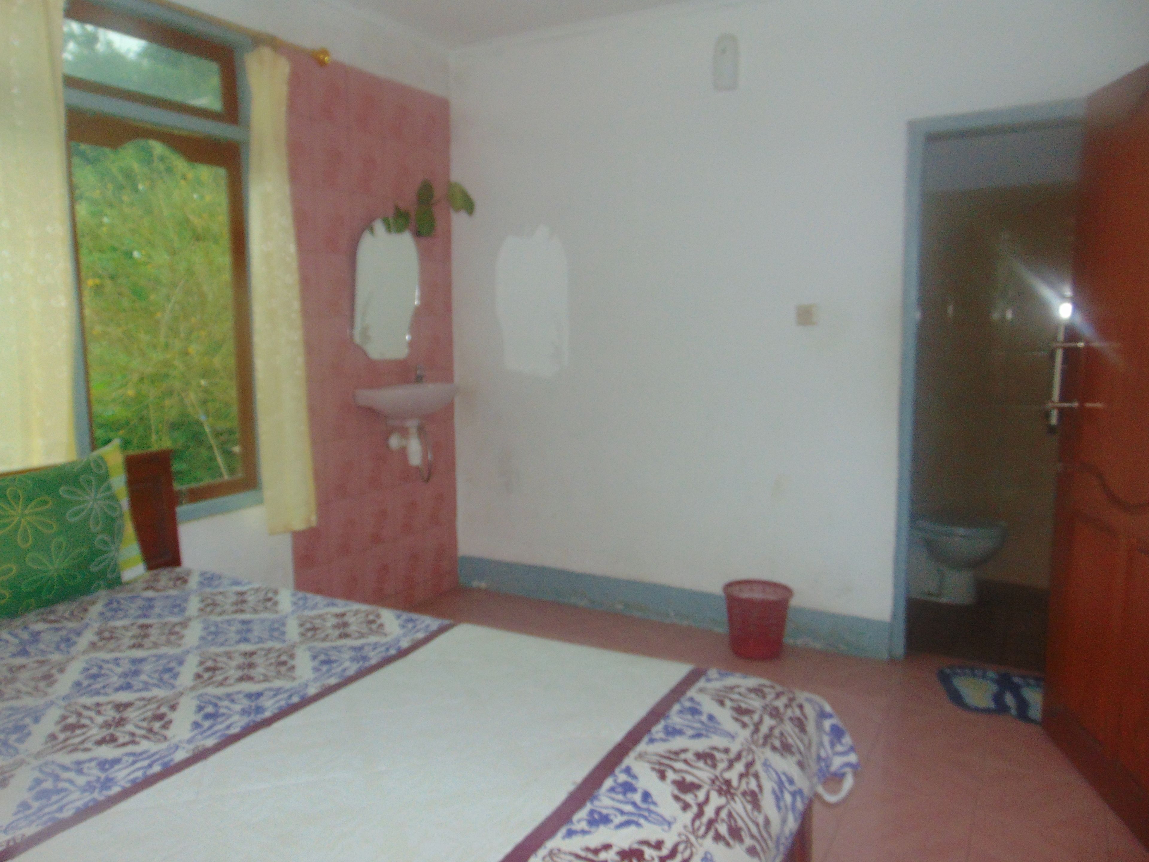 Una camera da letto con un letto, una finestra, un lavandino e una porta che dà su un bagno.