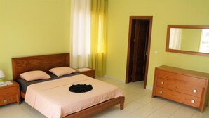 Un dormitorio con una cama de madera, una mesita de noche, un aparador y un espejo.