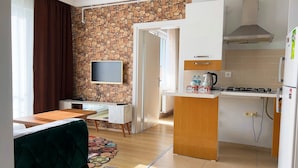 A compact kitchen with a stone wall, a flat-screen TV, a small dining area, and a kitchenette. - Edirne House (Edirne)