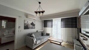 A modern living room with a grey sofa, a small table, a mounted picture, and a ceiling light fixture. - Edirne House (Edirne)
