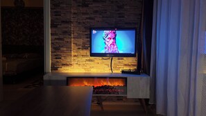 A television mounted on a stone wall, a fireplace with logs, and a bed in the background. - Edirne House (Edirne)