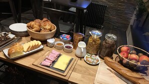 Un bufé de desayuno con cruasanes, jamón, queso, frutas y diversas opciones para untar.