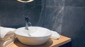 A bathroom with a round mirror, a white sink, and a wooden countertop.