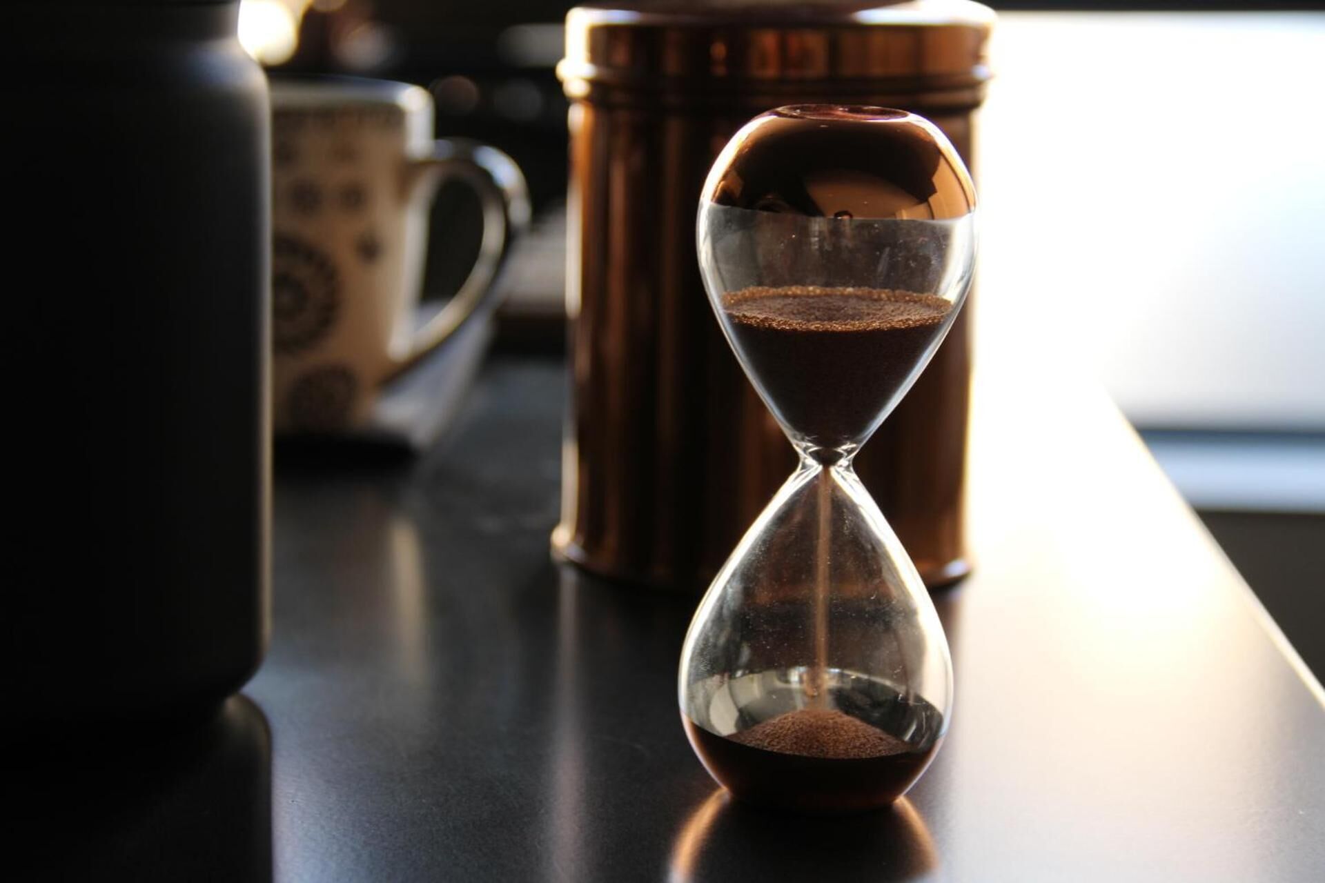An hourglass with coffee grounds on a table.