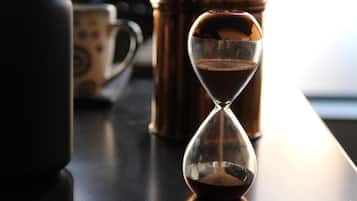 An hourglass with coffee grounds on a table.