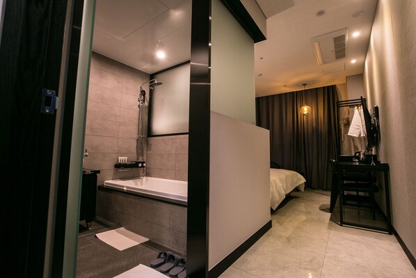 Une salle de bain d’hôtel moderne, dotée d’une baignoire, d’une douche et d’un meuble-lavabo avec un miroir.
