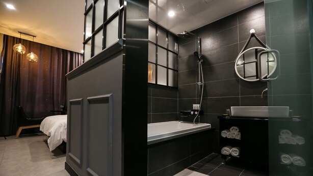 A modern bathroom with a bathtub, a sink, and a mirror. - Hotel Senne (Seoul)
