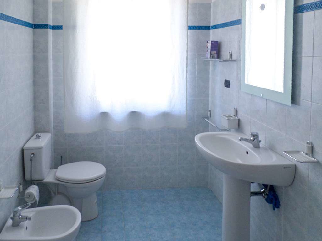 A bathroom with a toilet, bidet, sink, and a mirror.