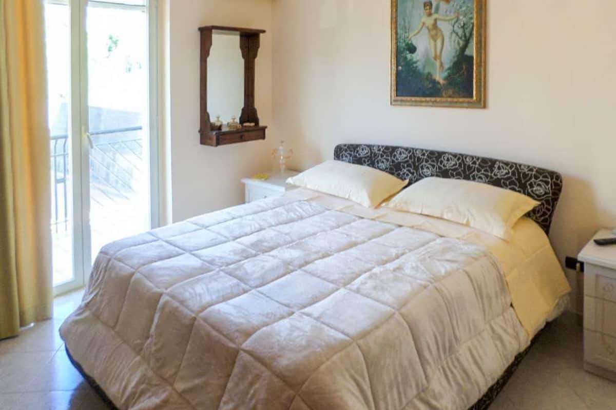Un dormitorio con una cama grande, una mesita de noche, un espejo y un cuadro en la pared.